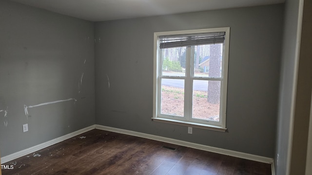 spare room with dark wood-type flooring, baseboards, and a wealth of natural light