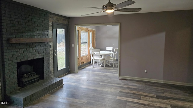 unfurnished living room with baseboards, a fireplace, wood finished floors, and a ceiling fan