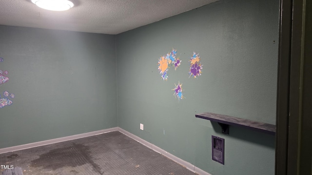 spare room featuring visible vents, a textured ceiling, and baseboards