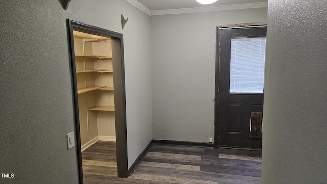 hallway with dark wood finished floors, a textured wall, baseboards, and ornamental molding