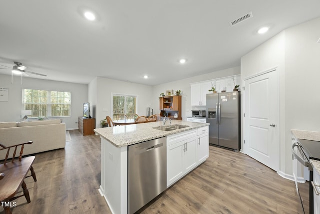 kitchen featuring visible vents, a center island with sink, stainless steel appliances, a ceiling fan, and a sink