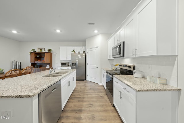 kitchen featuring visible vents, light wood finished floors, a sink, stainless steel appliances, and tasteful backsplash