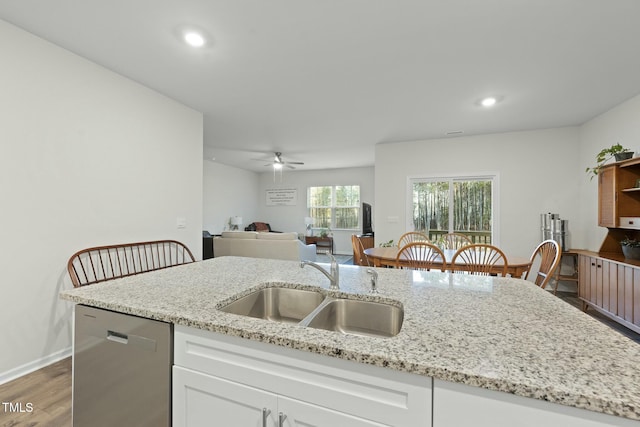 kitchen featuring a sink, light stone counters, stainless steel dishwasher, white cabinetry, and recessed lighting