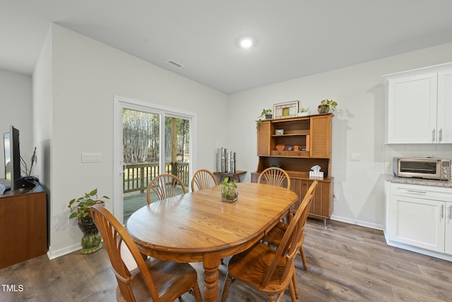 dining room with visible vents, a toaster, wood finished floors, and baseboards