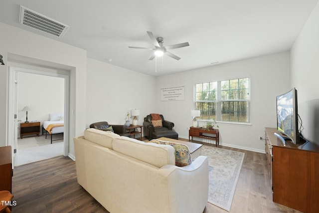 living area featuring visible vents, baseboards, dark wood-type flooring, and a ceiling fan