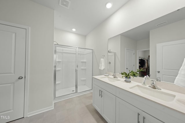 full bathroom featuring double vanity, visible vents, a stall shower, and a sink