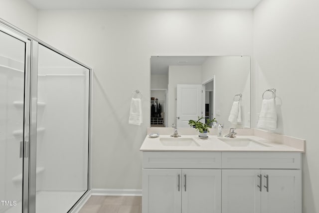 bathroom with double vanity, baseboards, a shower stall, and a sink