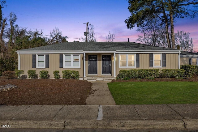 view of front of house with board and batten siding, a front lawn, and roof with shingles