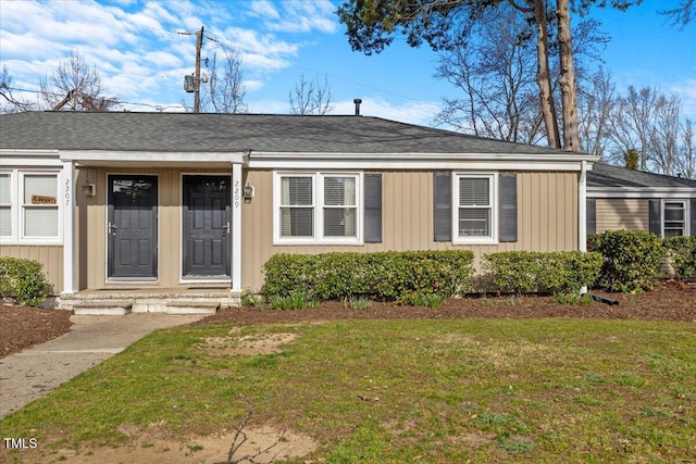 view of front of home with a front yard, board and batten siding, and roof with shingles