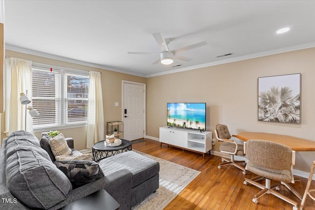 living area featuring visible vents, ceiling fan, baseboards, ornamental molding, and wood-type flooring