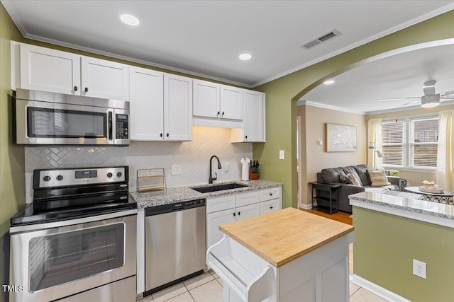 kitchen with visible vents, ornamental molding, a sink, stainless steel appliances, and light tile patterned floors