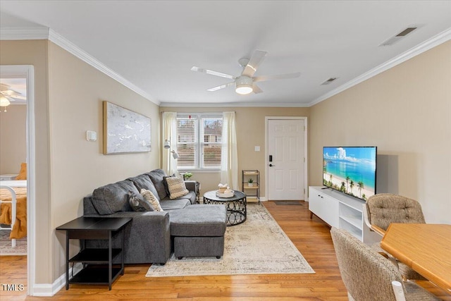 living room featuring wood finished floors, crown molding, a ceiling fan, and visible vents