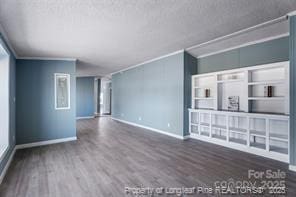 unfurnished living room featuring baseboards, wood finished floors, and ornamental molding