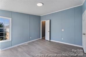 unfurnished bedroom featuring wood finished floors, baseboards, and ornamental molding