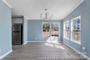 unfurnished dining area with vaulted ceiling, baseboards, an inviting chandelier, and wood finished floors