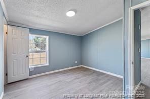 unfurnished bedroom with baseboards, a textured ceiling, and wood finished floors