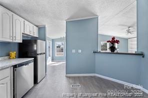 kitchen with white cabinetry, baseboards, stainless steel appliances, a textured ceiling, and a ceiling fan