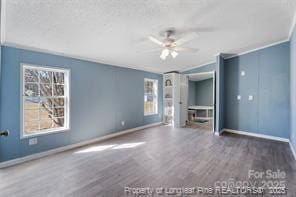 unfurnished bedroom featuring ceiling fan, baseboards, wood finished floors, and crown molding