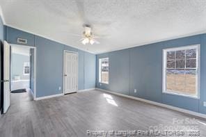 unfurnished bedroom featuring a textured ceiling, wood finished floors, baseboards, and vaulted ceiling