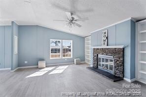 unfurnished living room featuring built in shelves, wood finished floors, a fireplace, ceiling fan, and vaulted ceiling