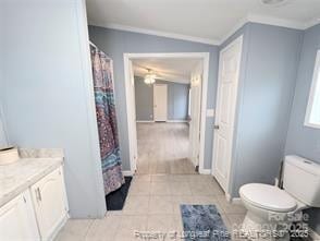 bathroom with tile patterned flooring, toilet, vanity, and ornamental molding