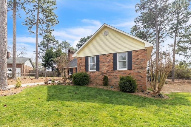 view of home's exterior featuring a yard, fence, and brick siding