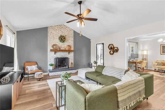 living area with light wood-type flooring, lofted ceiling, ceiling fan, and a fireplace