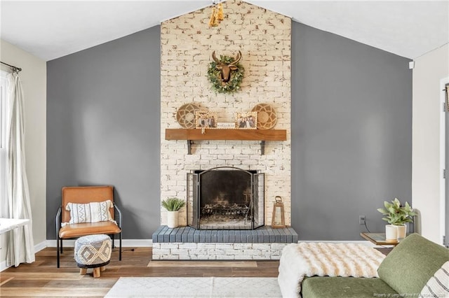 living area with a fireplace, vaulted ceiling, wood finished floors, and baseboards