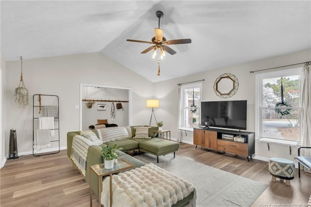 living area with vaulted ceiling, a healthy amount of sunlight, light wood-type flooring, and ceiling fan