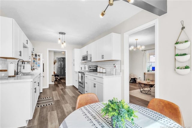 kitchen with dark wood finished floors, appliances with stainless steel finishes, white cabinetry, and light countertops