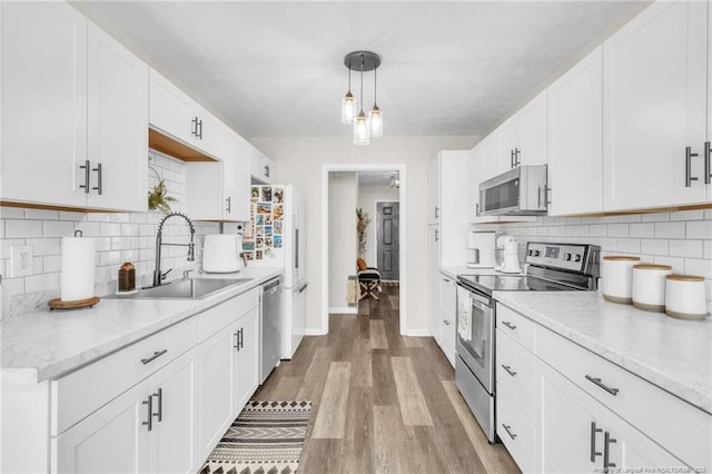 kitchen featuring appliances with stainless steel finishes, white cabinetry, light wood-type flooring, and a sink