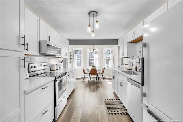 kitchen with light countertops, decorative backsplash, appliances with stainless steel finishes, wood finished floors, and a sink