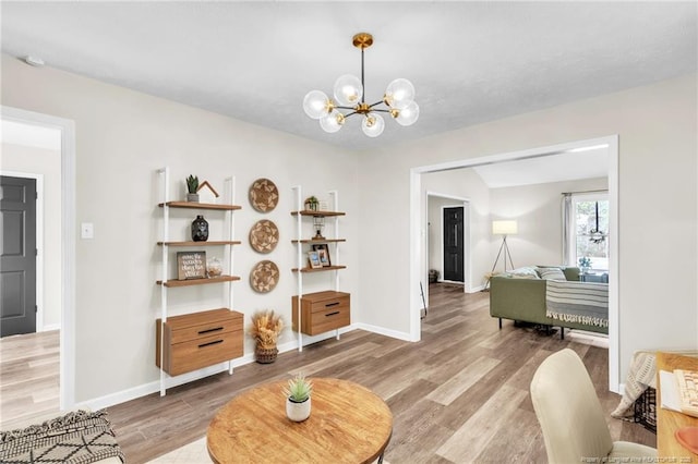 sitting room featuring a chandelier, light wood finished floors, and baseboards