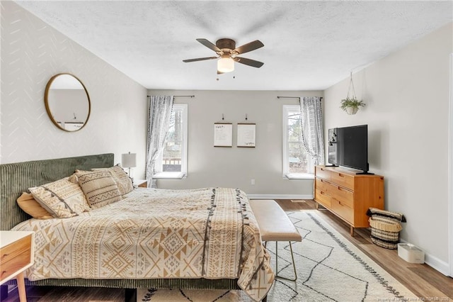 bedroom with a textured ceiling, baseboards, and wood finished floors