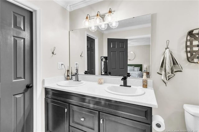 full bathroom featuring double vanity, ornamental molding, toilet, and a sink