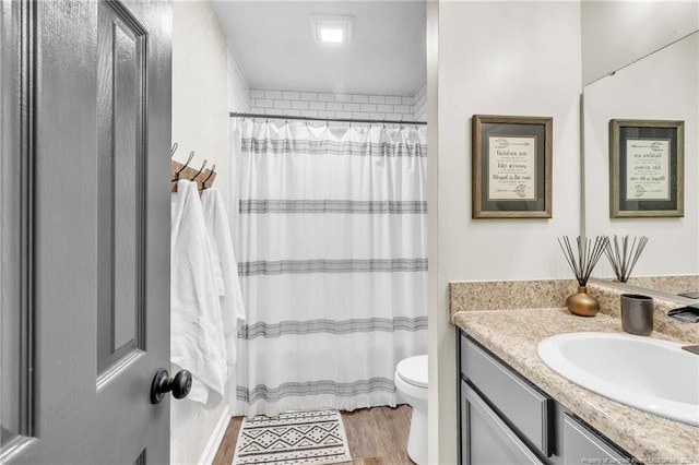 bathroom with toilet, vanity, a shower with curtain, and wood finished floors