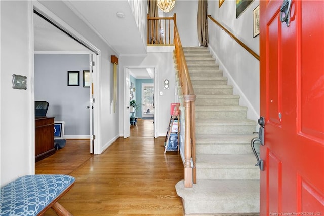 foyer featuring stairway, wood finished floors, baseboards, and ornamental molding