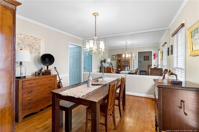 dining area with an inviting chandelier, light wood-style flooring, and crown molding