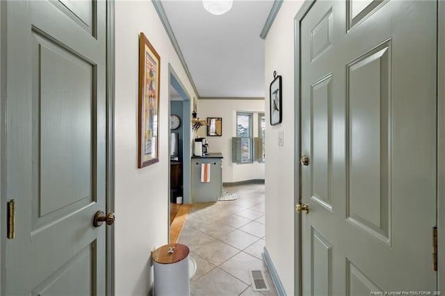 corridor featuring light tile patterned floors, visible vents, crown molding, and baseboards