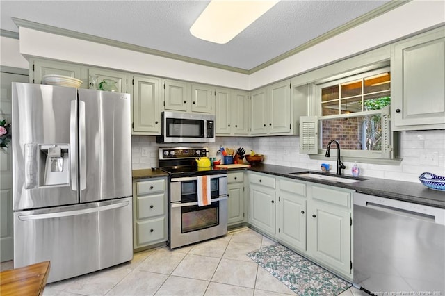 kitchen with light tile patterned flooring, a sink, appliances with stainless steel finishes, a textured ceiling, and tasteful backsplash