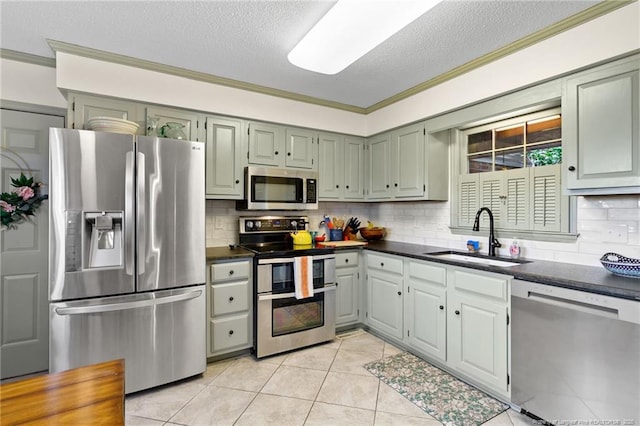 kitchen with a sink, dark countertops, appliances with stainless steel finishes, and ornamental molding