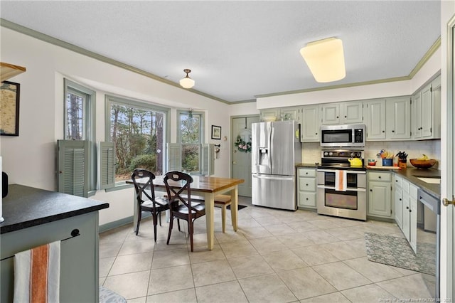 kitchen featuring dark countertops, tasteful backsplash, appliances with stainless steel finishes, and ornamental molding