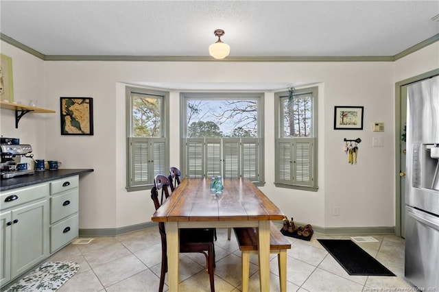 dining space with a textured ceiling, light tile patterned floors, baseboards, and ornamental molding