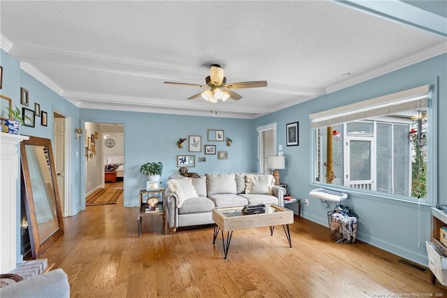 living room featuring beamed ceiling, a textured ceiling, light wood-style floors, and ceiling fan