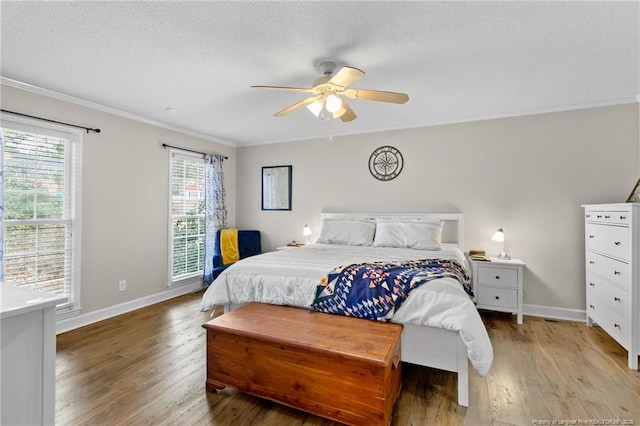 bedroom featuring light wood-type flooring, baseboards, a textured ceiling, and ornamental molding