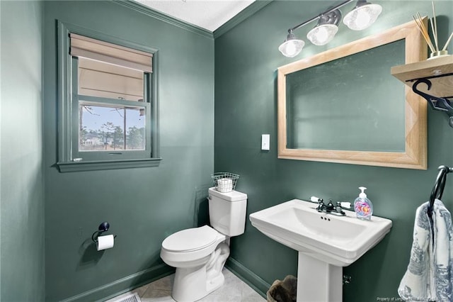 half bathroom featuring tile patterned flooring, toilet, baseboards, and a sink