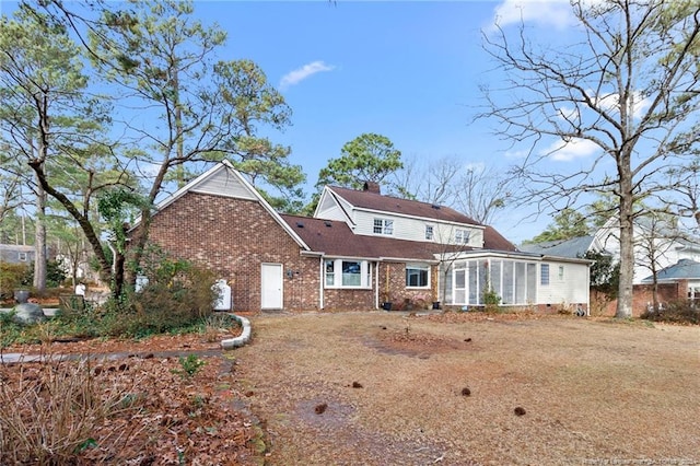 view of front of property with brick siding, a chimney, and a sunroom