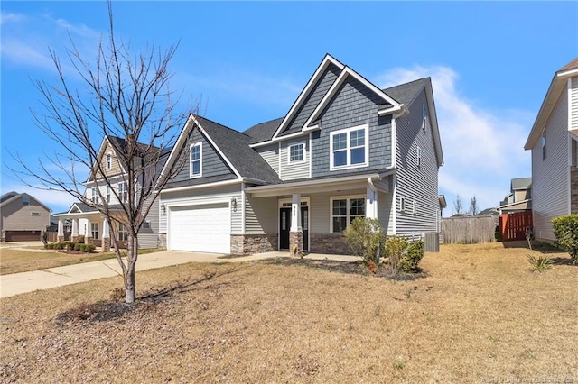 craftsman house featuring stone siding, fence, covered porch, concrete driveway, and a garage