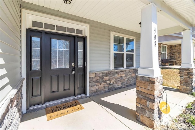 doorway to property featuring stone siding and covered porch