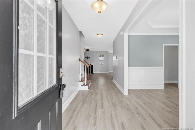 entrance foyer featuring stairway, a decorative wall, light wood-style flooring, and a wainscoted wall